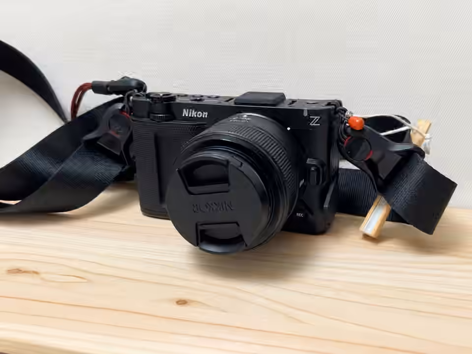 木の机に、レンズと黒いストラップを付けて置いたNikon ZR