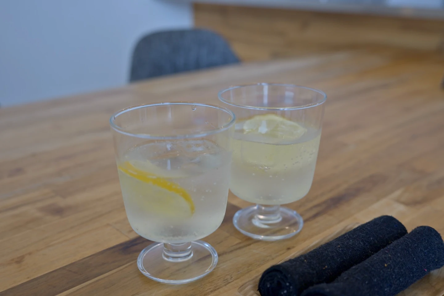 木のテーブルに置かれた、柑橘の薄切りと氷が入った二つのグラス